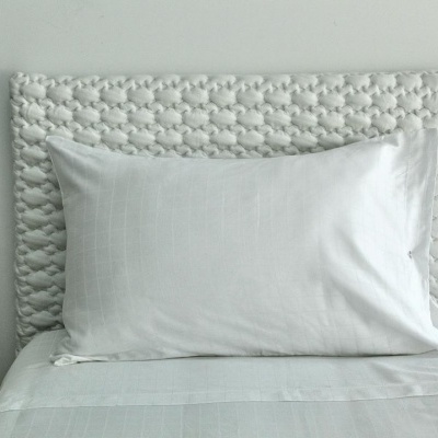 Cama com almofada branca e cabeceira em corda trançada