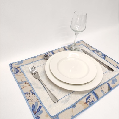 Conjunto de mesa com prato branco, talheres de inox, taça de vidro e guardanapo decorado.