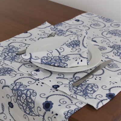 Guardanapo e toalha de mesa brancos com padrão azul floral e arabescos