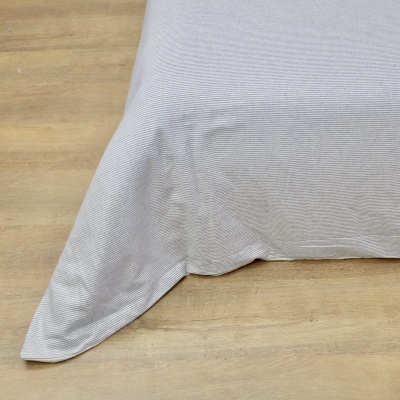 Colcha cinzenta clara com riscas finas sobre chão de madeira clara