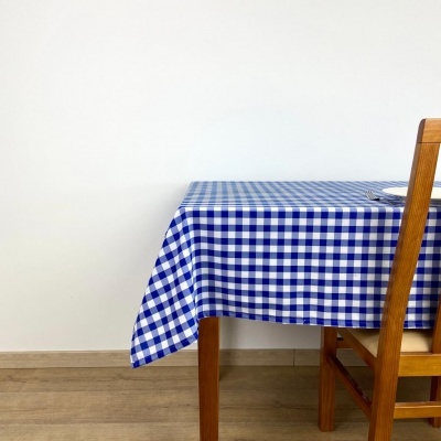 toalha de mesa azul e branca xadrez sobre mesa de madeira com cadeira em parede branca