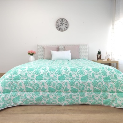 Edredão floral verde aqua e branco numa cama com cabeceira cinza e almofadas