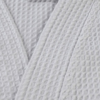 Detalhe de tecido branco com textura de colmeia e costuras.