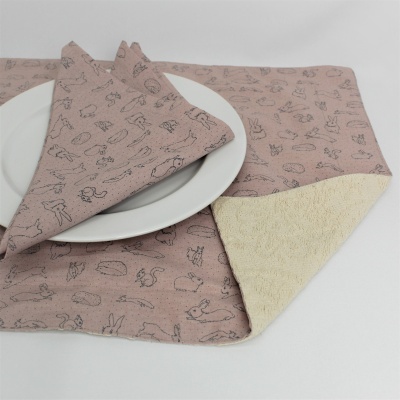 Guardanapo e toalhete rosa com padrão preto de animais e objetos sobre prato branco