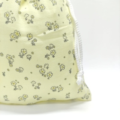 Saco de tecido amarelo claro com padrão floral e cordão branco
