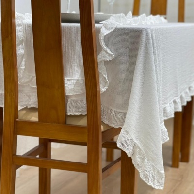 Mesa de madeira clara com toalha branca e cadeiras de madeira clara