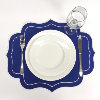 Conjunto de jantar com pratos brancos, talheres metálicos, copo de vidro e individual azul decorativo
