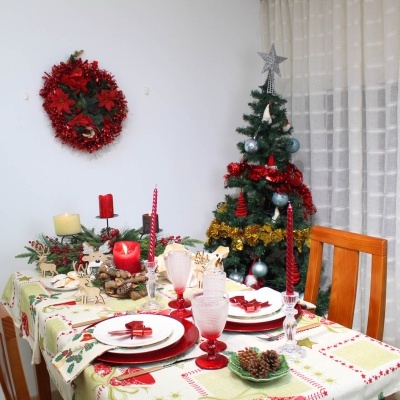 Mesa de jantar natalícia com árvore de Natal e guirlanda vermelha na parede