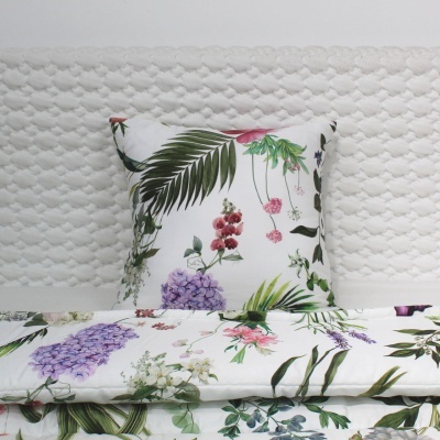 Almofada e edredão florais multicoloridos em cama com cabeceira branca texturizada