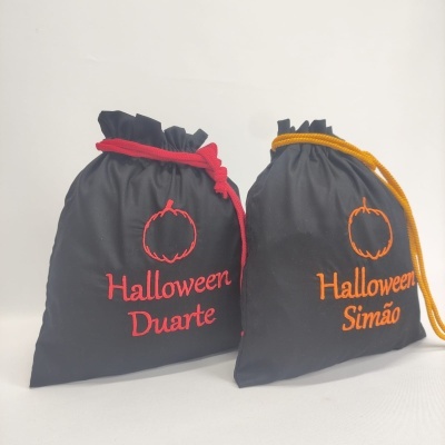 Dois sacos de tecido preto com fecho de cordão e texto colorido