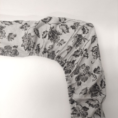 Capa de tecido cinza com padrão floral preto e elástico numa superfície branca.