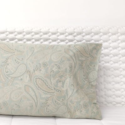 Almofada decorativa com padrão floral em tons suaves sobre superfície texturada branca