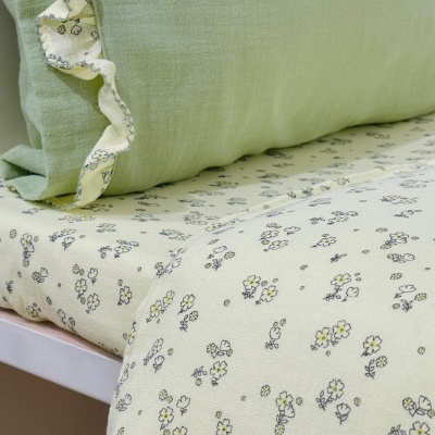 Cama com almofada verde e conjunto de roupa de cama floral