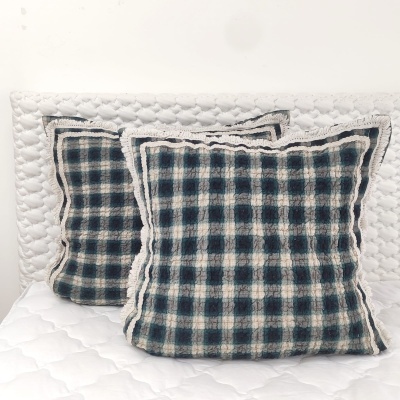 Almofadas xadrez azul e branco com franjas numa cama branca matelassada