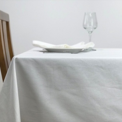 Mesa com toalha branca, cadeira de madeira, prato branco com guardanapo e taça de vidro