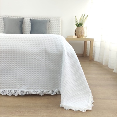 Colcha de cama branca texturizada com borda rendada e almofadas cinzentas