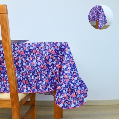 Toalha de mesa azul escuro com padrão floral colorido e volante franzido nas bordas