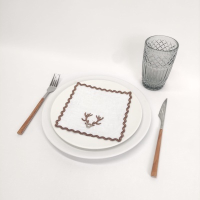 Conjunto de mesa com prato, guardanapo decorativo, talheres com cabos de madeira e copo de vidro cinzento.
