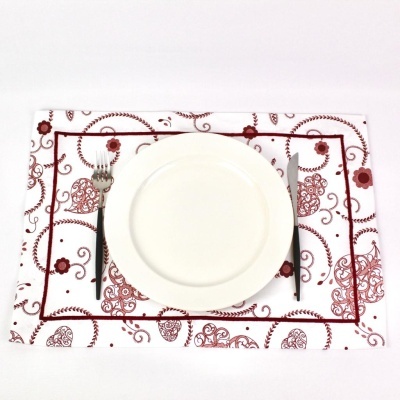 Jogo americano branco com padrão vermelho, prato branco, garfo e faca