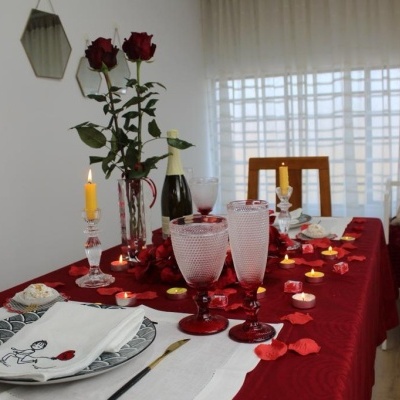 Mesa de jantar com decoração romântica e elementos vermelhos e rosa.