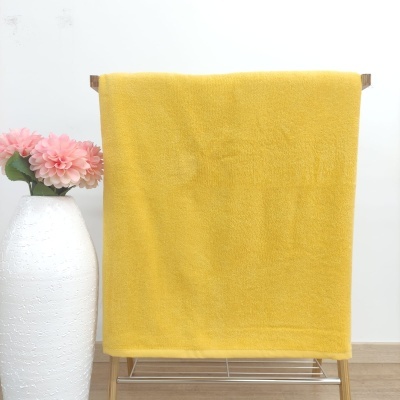 Toalha amarelo mostarda pendurada numa estrutura de madeira com vaso branco e flores cor de rosa