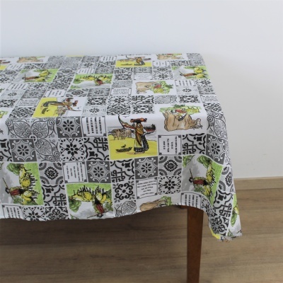 Toalha de mesa decorativa com padrão de azulejos e citações religiosas numa mesa de madeira