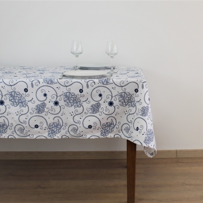 Mesa com toalha branca e padrão azul, dois copos e um prato com talheres