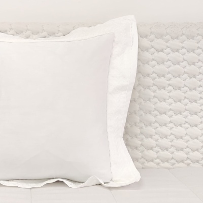 Travesseiro branco com fronha texturizada em cama com cabeceira estampada