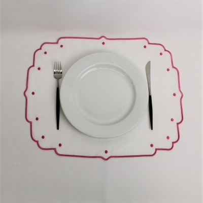 Jogo americano branco com borda rosa, prato branco, garfo e faca com cabos pretos.