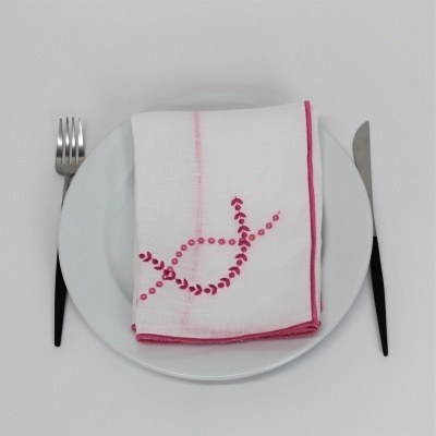 Pratos brancos com guardanapo branco e rosa e talheres com cabos pretos