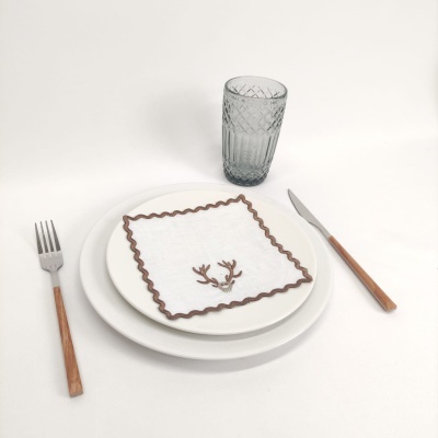 Conjunto de mesa com guardanapo decorado e talheres de madeira, copo texturizado cinzento