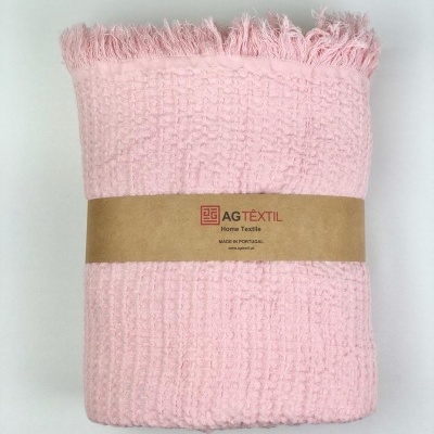 Manta cor-de-rosa com padrão waffle e franjas, embalada com faixa de papel castanha