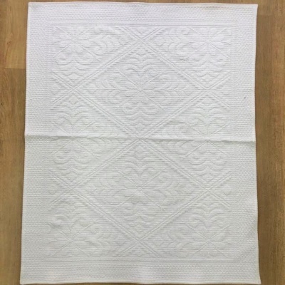 Guardanapo branco de tecido com padrão em relevo sobre madeira clara
