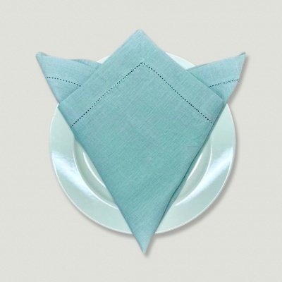 Guardanapo azul claro dobrado sobre prato branco