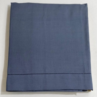Guardanapo de tecido azul dobrado com borda costurada preta