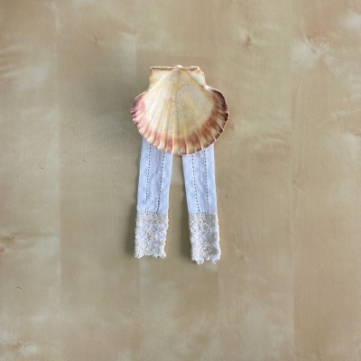 Mangas brancas com renda presas numa concha natural creme e rosa