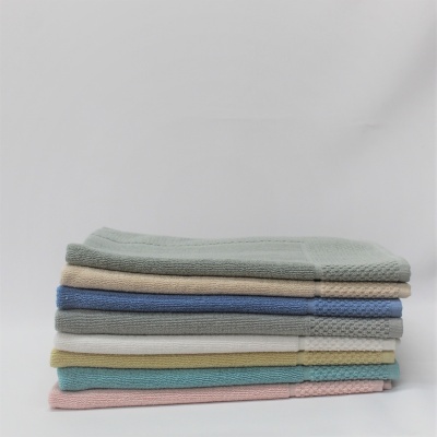Toalhas dobradas em tons pastel empilhadas sobre fundo branco
