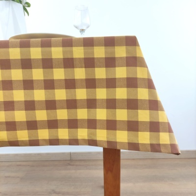 Toalha de mesa xadrez amarelo e castanho sobre mesa de madeira