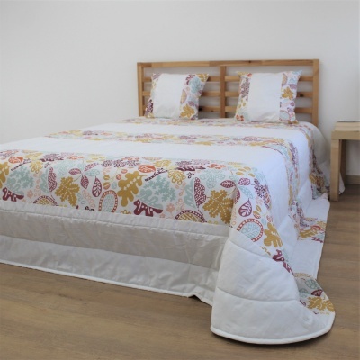 Colcha de cama branca com padrão de folhas coloridas e almofadas decorativas