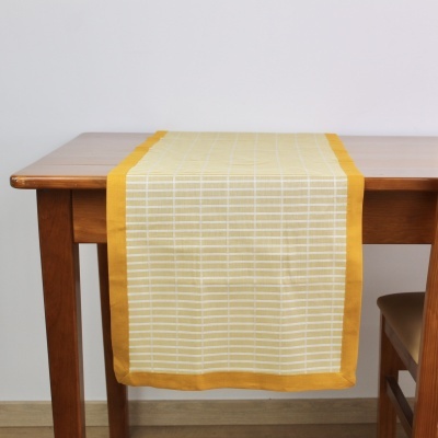 Caminho de mesa amarelo com riscas brancas sobre mesa de madeira clara