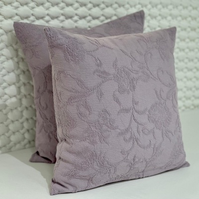 Duas almofadas lilás com padrão floral bordado sobre superfície branca