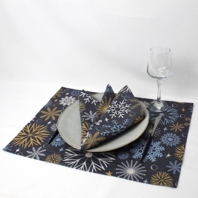 Conjunto de jantar com prato cinza claro, guardanapo e individual com estampa de flocos de neve e copo de vidro.