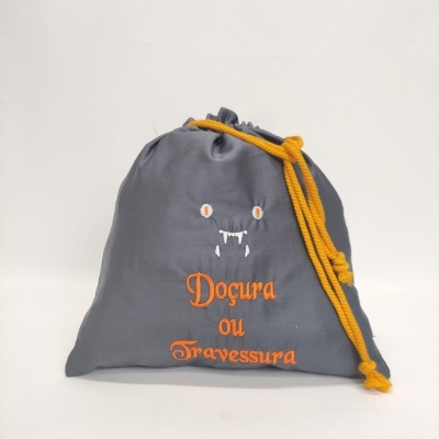 Saco cinzento com cordão amarelo e bordado laranja com olhos e presas brancas.