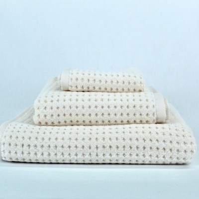 Conjunto de três toalhas de banho cor creme empilhadas