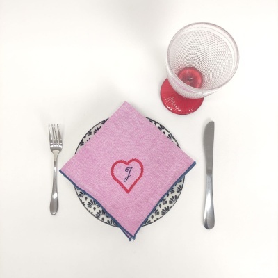 Talheres, prato decorado, guardanapo bordado e copo com fruta