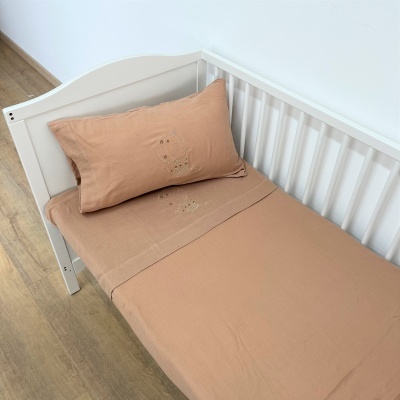 Cama branca com lençóis bege claro e bordado delicado