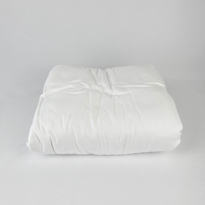 Edredão branco dobrado sobre superfície branca