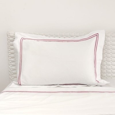 almofada branca com bordado vermelho sobre colchão branco