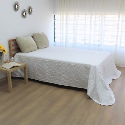 Quarto com cama de madeira clara e colcha branca texturada