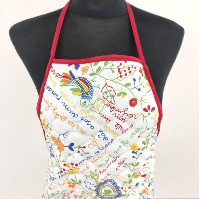 Avental branco com padrão colorido de flores e peixes e texto multicolorido